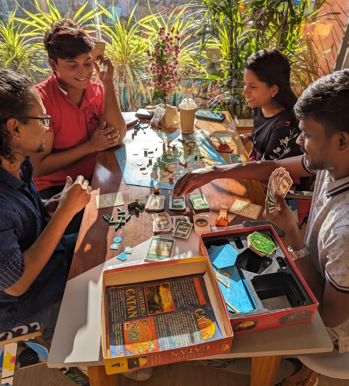 A group of four people playing Catan and having fun while playing