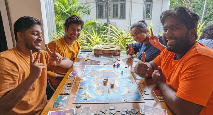 A picture of four people enthusiastically playing a board game