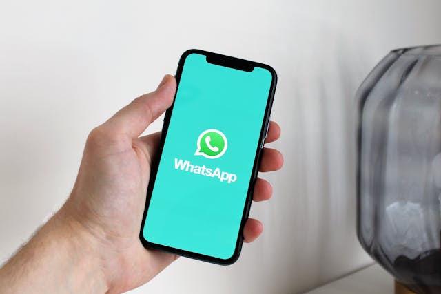 A phone held in hand, with a big WhatsApp icon displayed on the screen